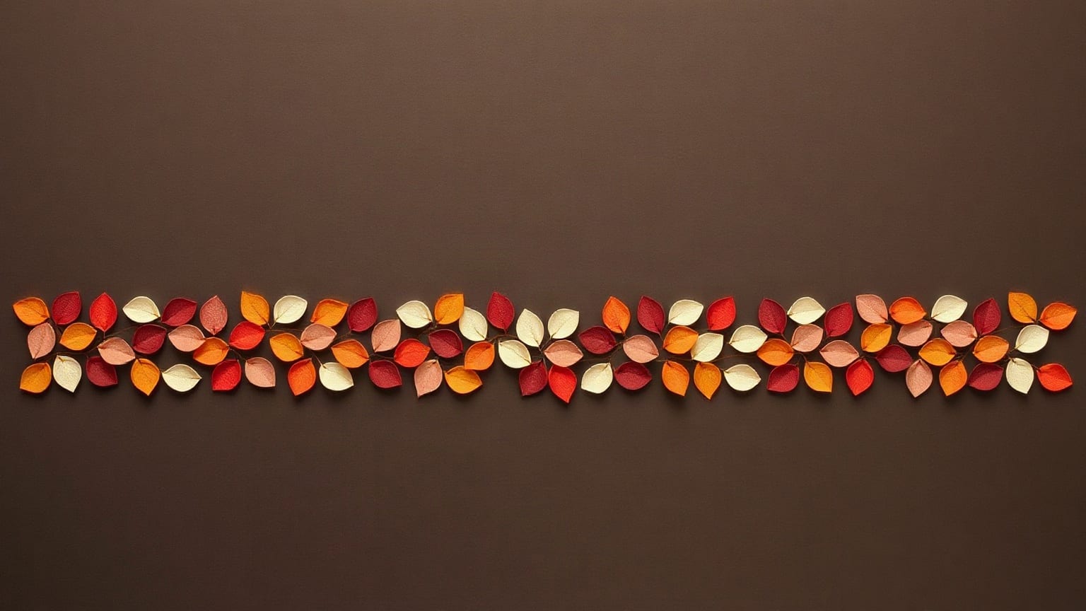A long single band of small paper petals in red, orange, cream and pink laid edge to edge across a dark brown ground, empty above and below